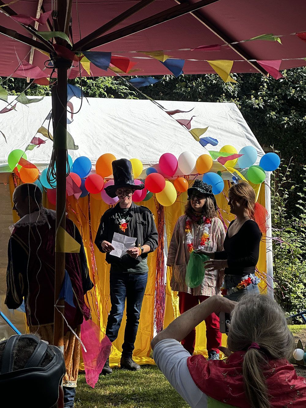 Eine Gruppe von Menschen steht vor einem Zelt mit Luftballons.