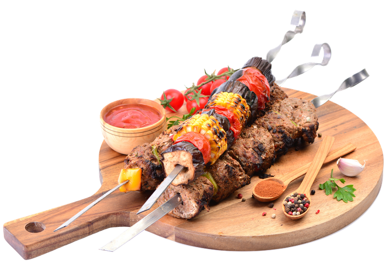 Brochettes grillées de légumes et sauce, servies sur une planche en bois avec un petit bol de sauce.