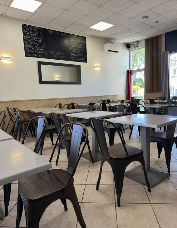 Salle à manger de café vide avec chaises en métal noir et tables.