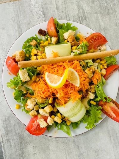 Salade fraîche composée de laitue, maïs, tomates, concombre, carottes râpées et quartiers de citron.