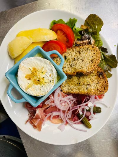 Assiette avec œufs au plat, pain grillé, pommes de terre, tomate, salade verte et oignons rouges émincés.
