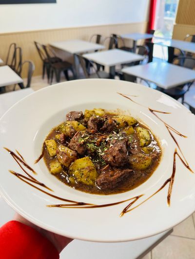 Assiette blanche avec un plat en sauce foncée, présentée dans la salle à manger d'un restaurant.