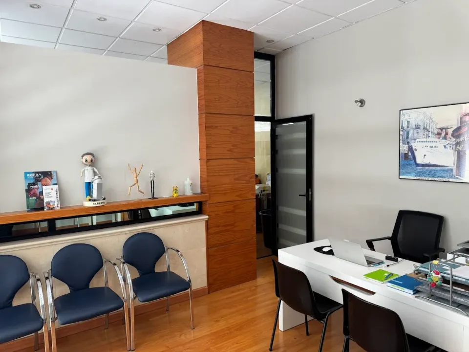 Sala de espera con sillas, escritorio, obras de arte y pilar de madera.