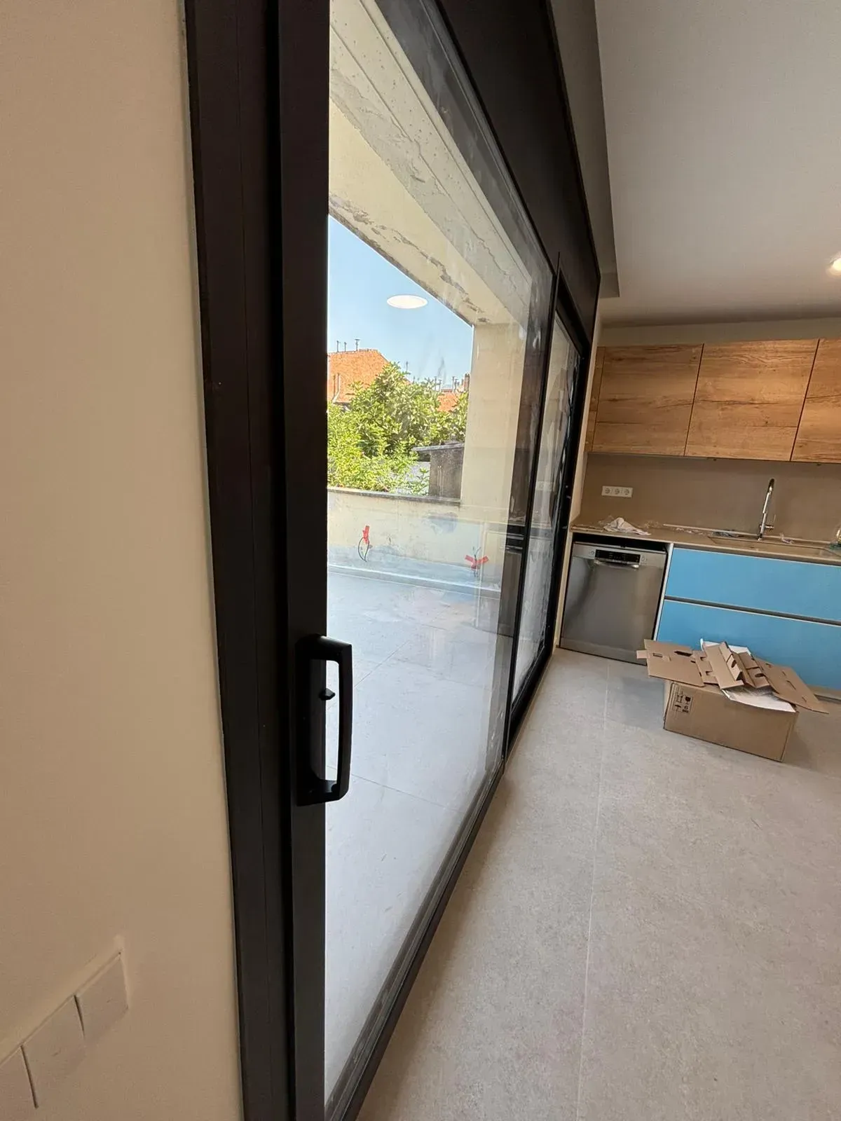 Puerta corrediza de vidrio con acceso a un patio exterior. Los gabinetes de cocina son visibles.