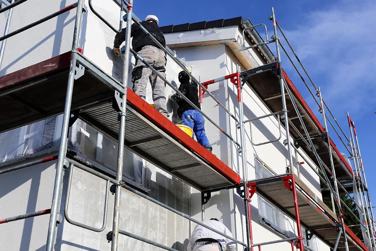 Deux hommes sur un échafaudage qui procèdent à un ravalement de façade