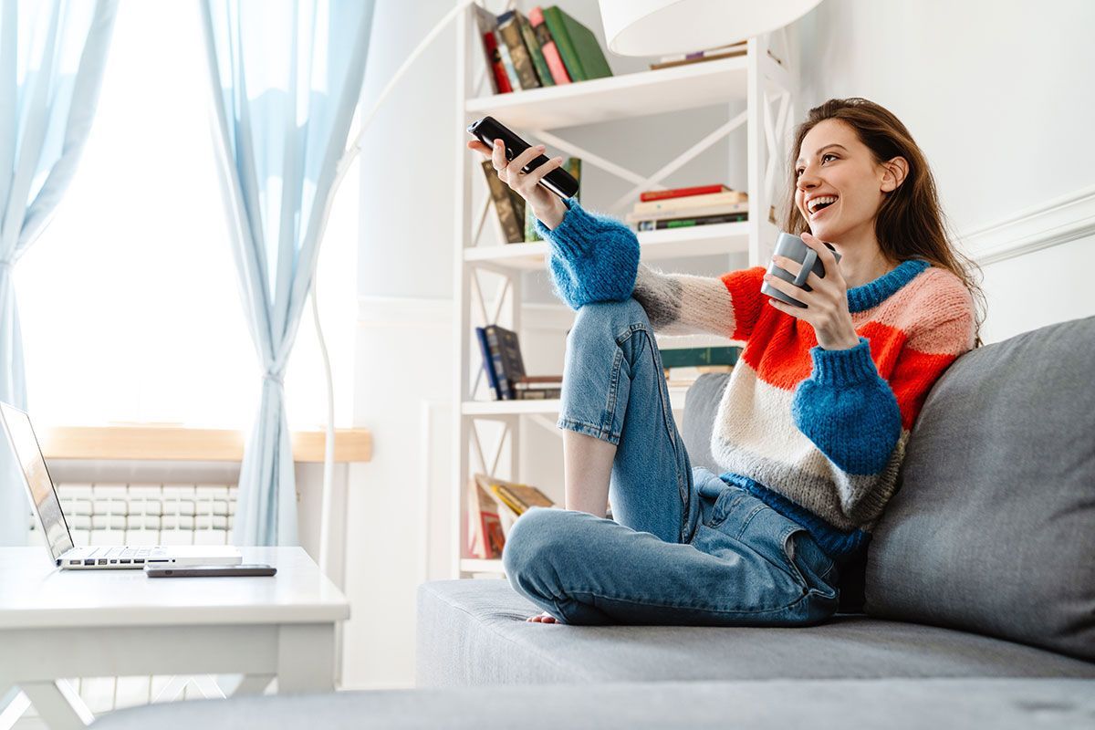 Femme tenant une tasse de café et qui regarde la télévision