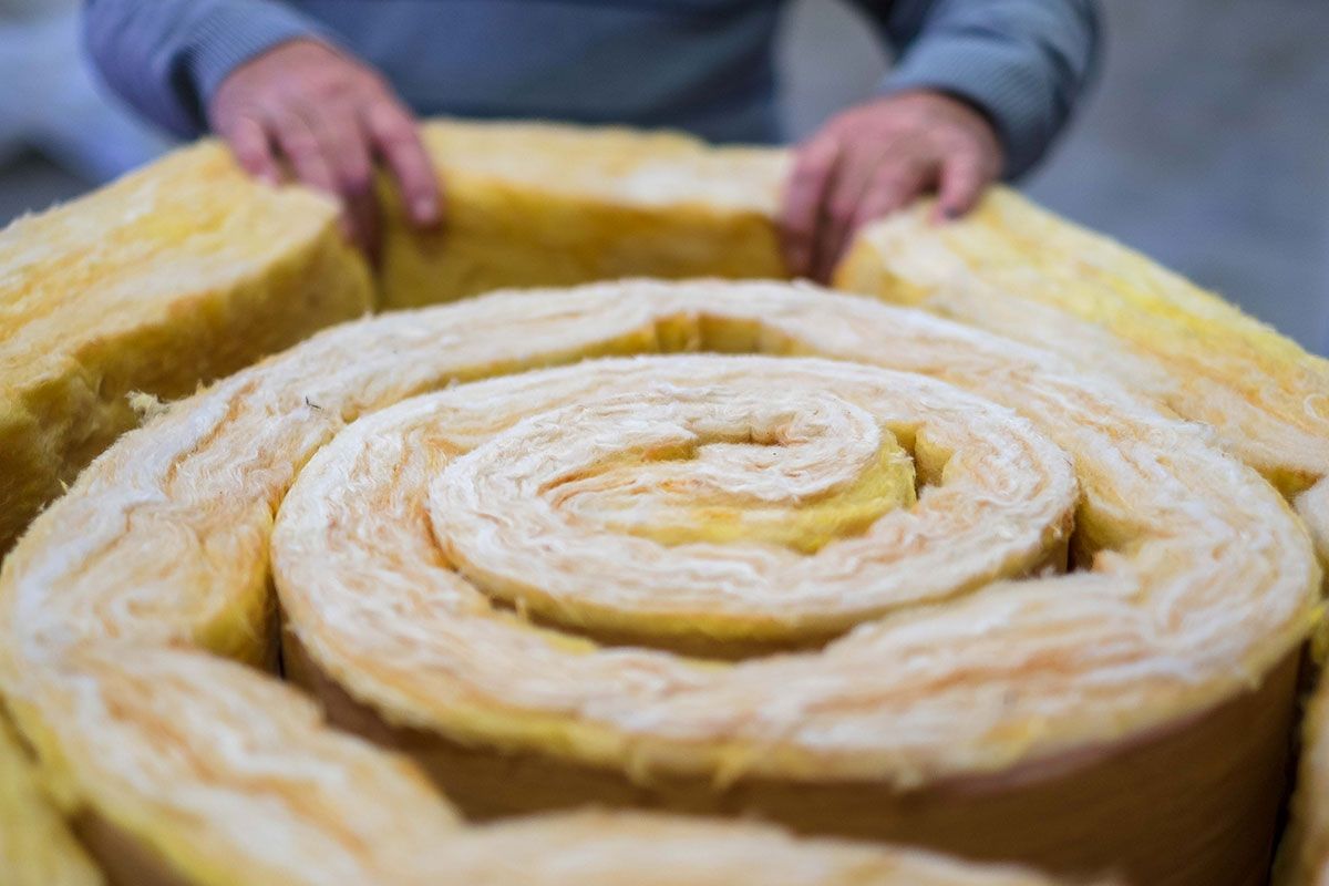 Focus sur les mains d'un homme qui tient un rouleau de laine de verre