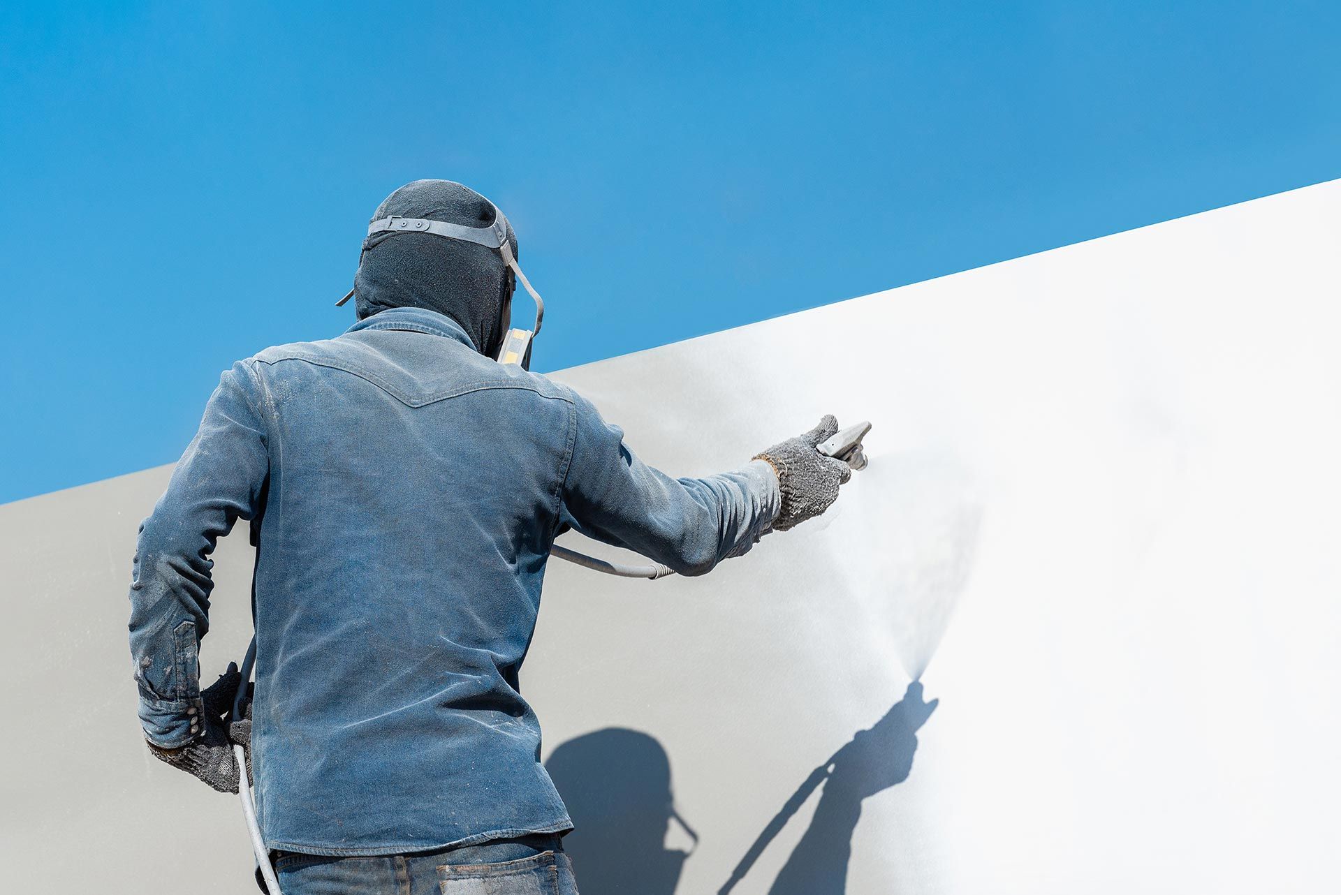 Homme qui peint un mur au pistolet