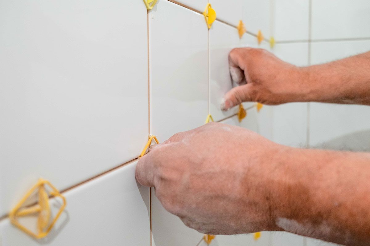 Homme qui pose du carrelage au mur