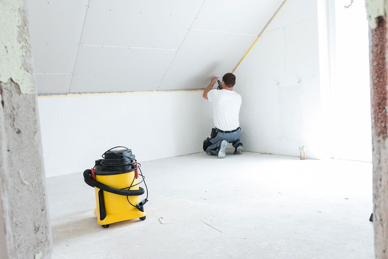 Homme qui pose du Placo et un aspirateur jaune