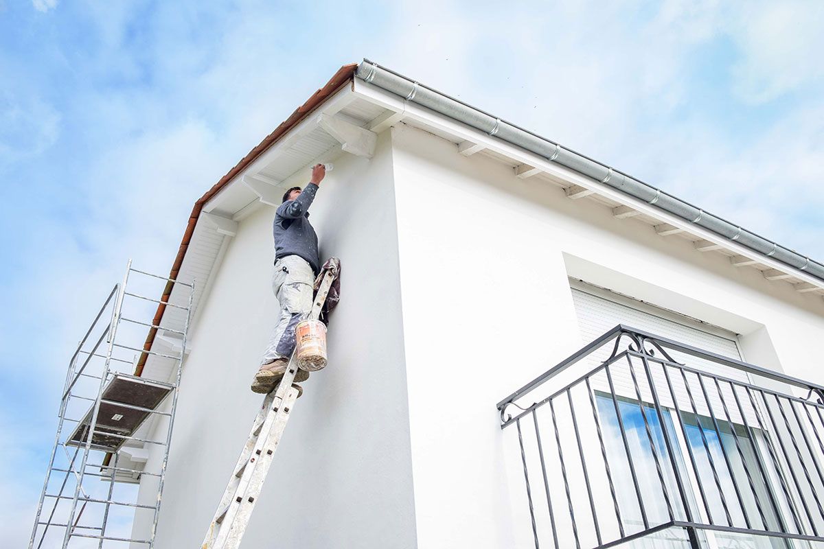 Peintre sur une échelle qui repeint des bandeaux de rive