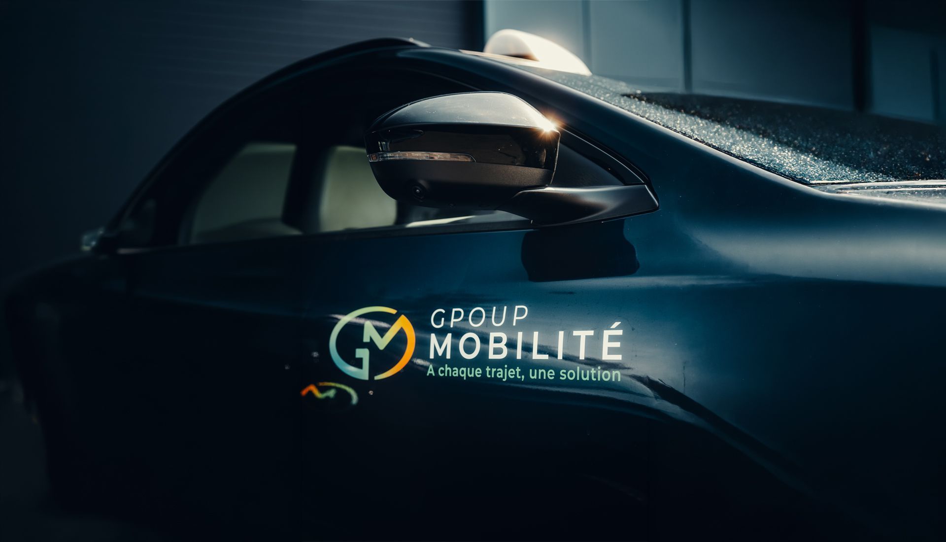 Voiture bleu foncé avec le logo et l'inscription « Groupe Mobilité » sur le panneau latéral
