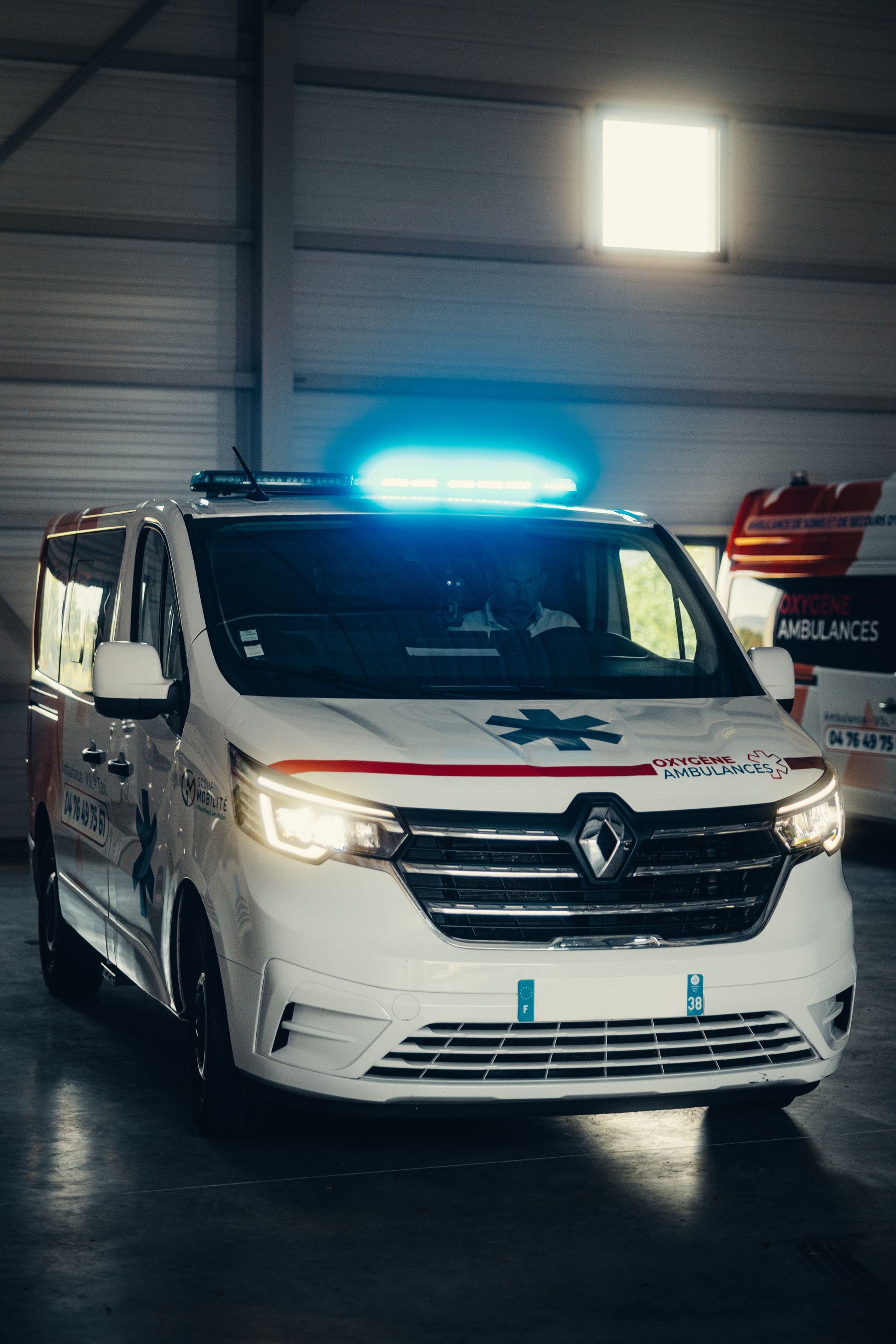 Fourgon d'intervention Renault blanc avec gyrophare bleu dans un garage, vue de face