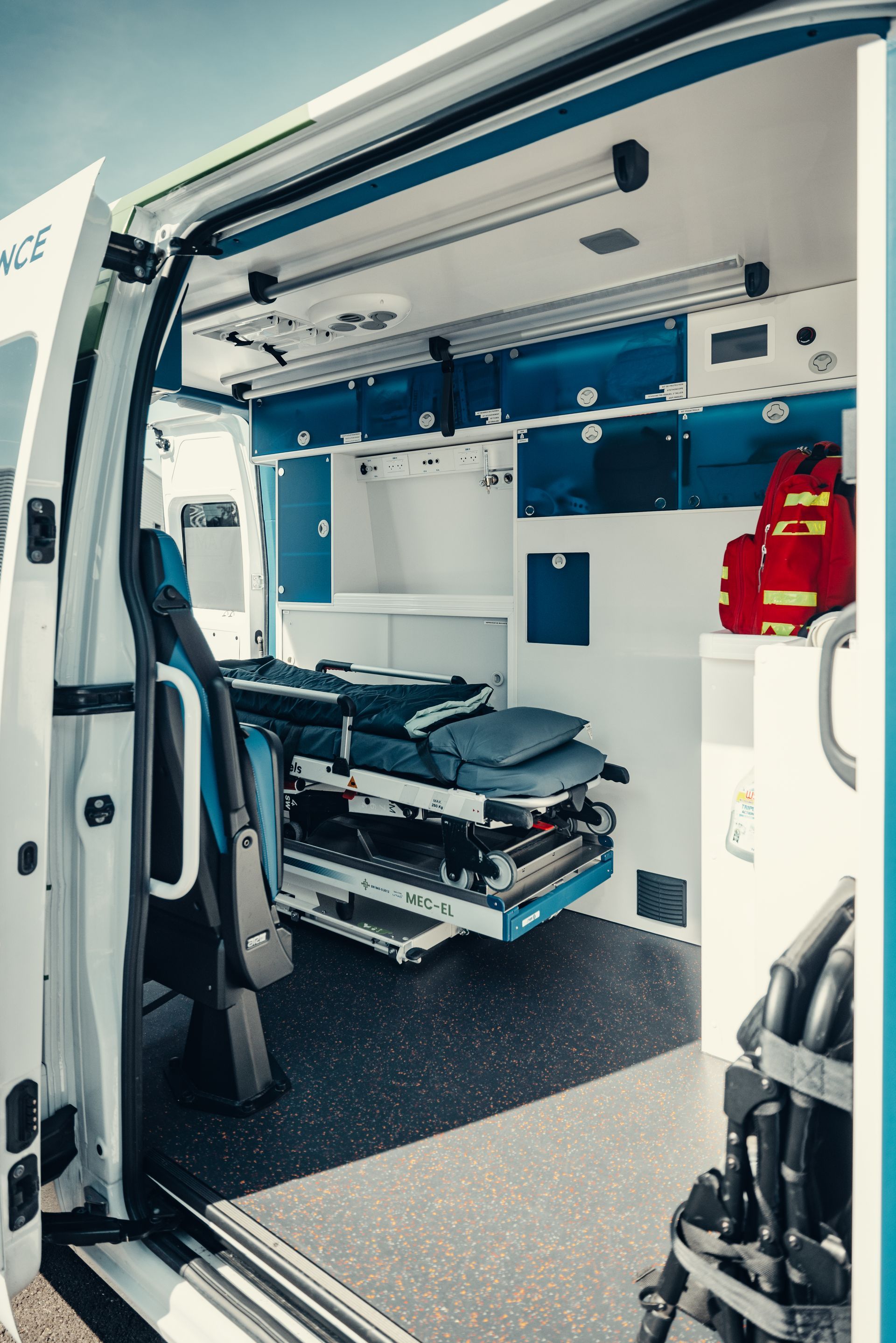 À l'intérieur d'une ambulance, on aperçoit une civière, des armoires et du matériel médical.