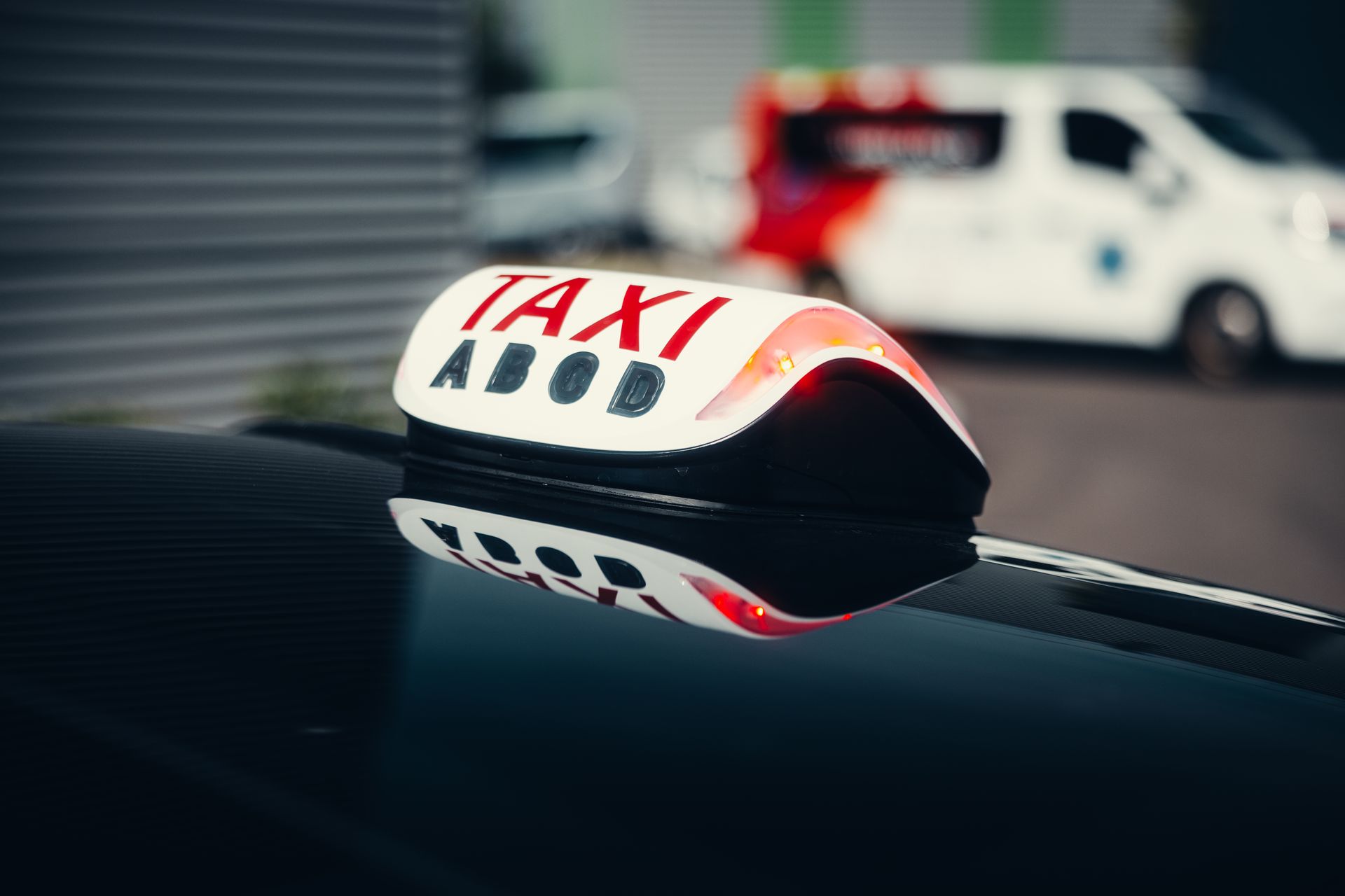 Panneau publicitaire de taxi sur le toit d'une voiture, avec un véhicule blanc flou en arrière-plan.