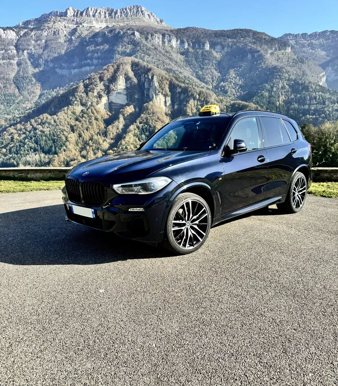 SUV noir garé sur une route avec des montagnes en arrière-plan