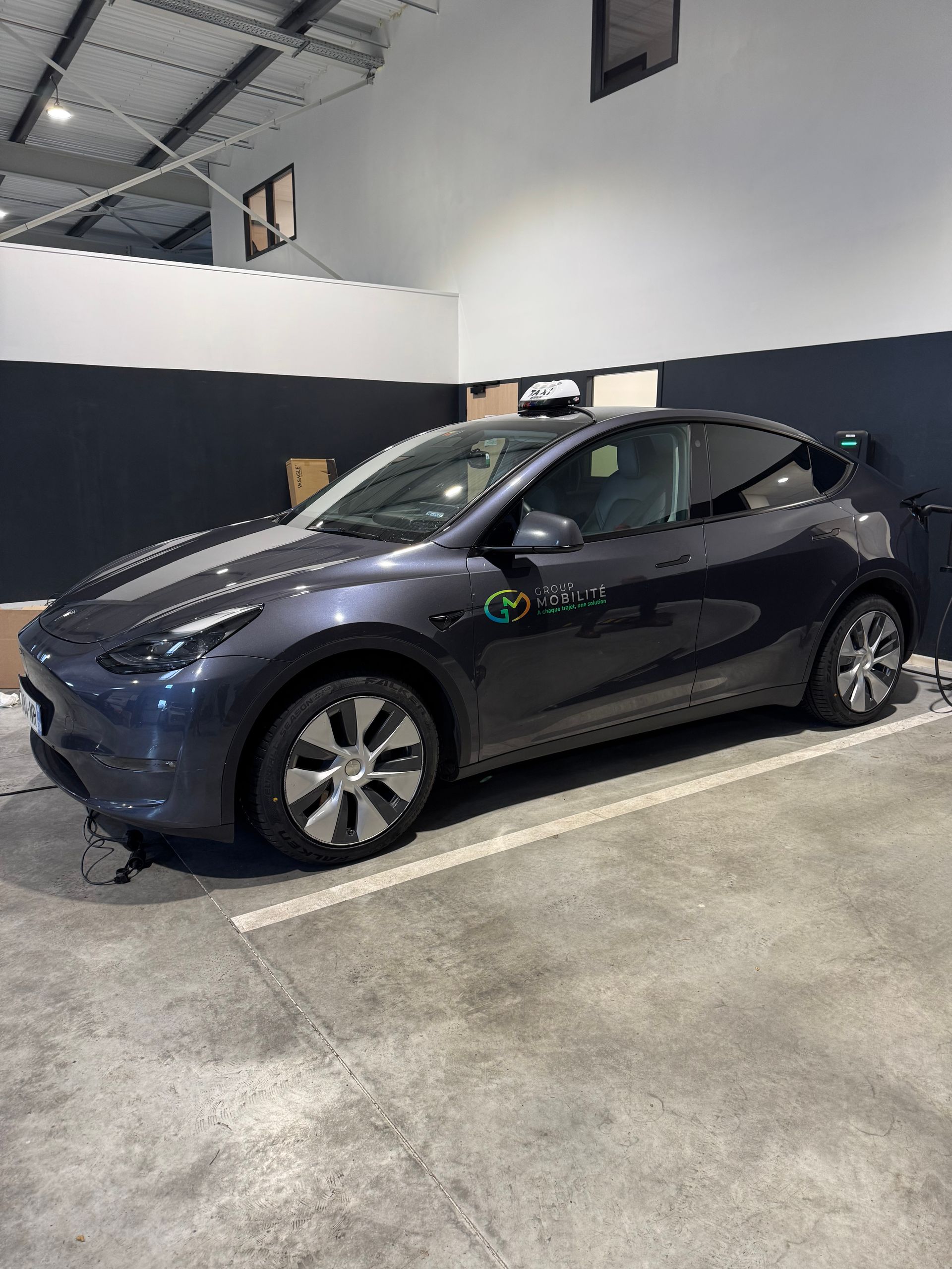 SUV électrique gris foncé stationné dans un garage intérieur, en charge à une borne murale.
