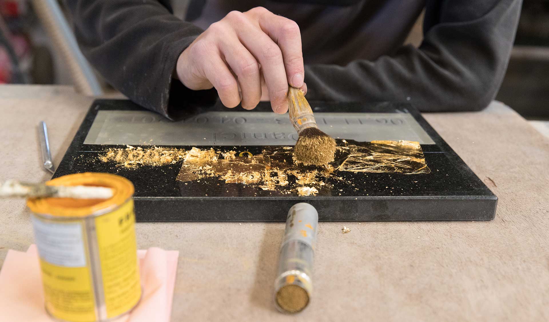 Une main applique de la dorure sur une gravure
