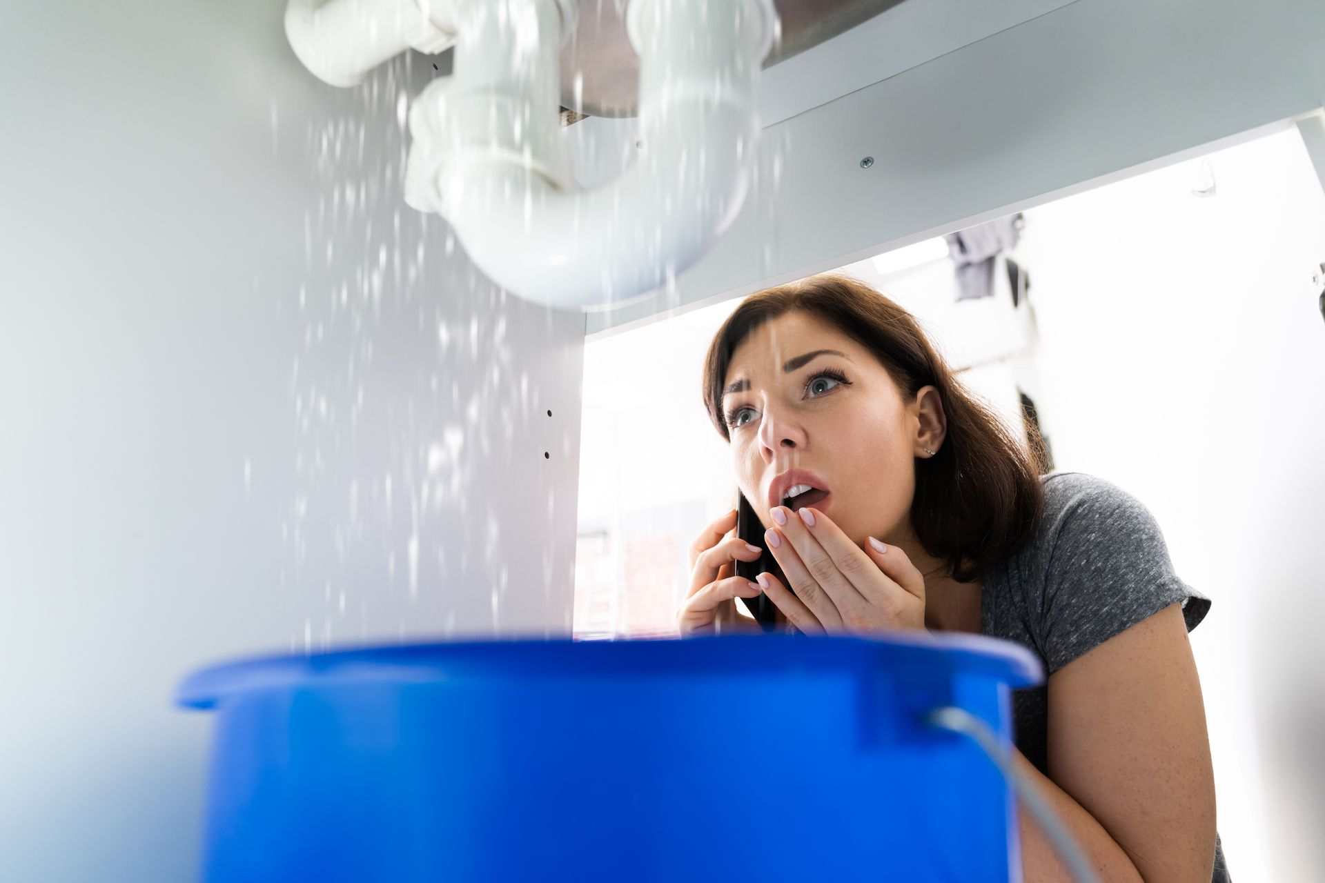 Une femme découvre une grosse fuite d'eau sous son lavabo.