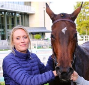 Femme en veste bleue qui tient un cheval