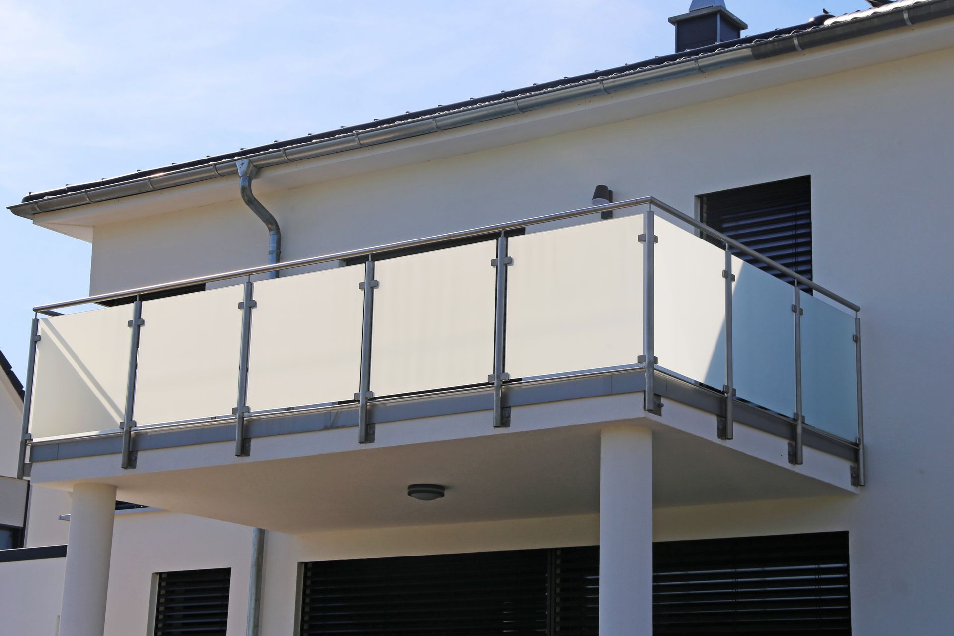 Ein weißes Haus mit einem Balkon mit Glasgeländer