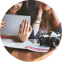 Dos mujeres mirando una tableta junto a un mapa de guía turística