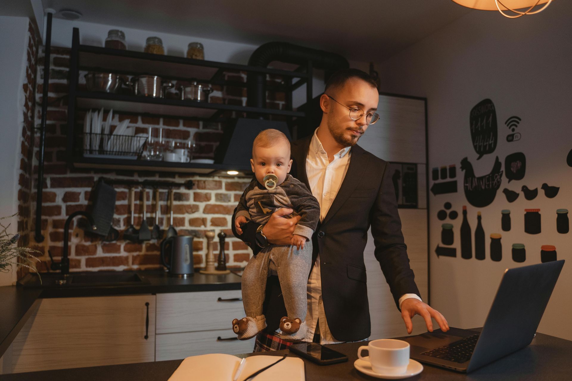 Ein Mann hält ein Baby, während er einen Laptop benutzt.