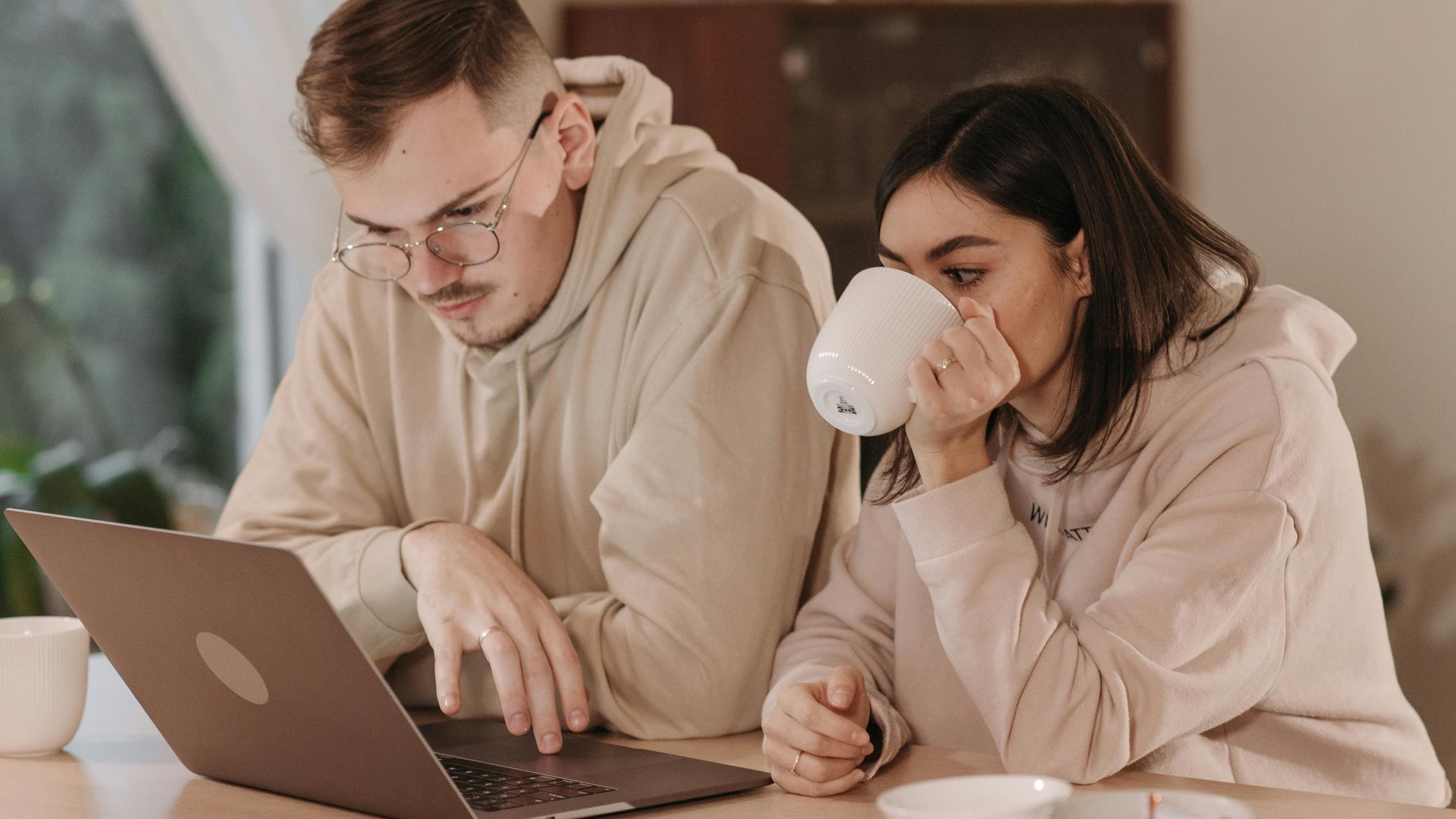 Ein Mann und eine Frau sitzen an einem Tisch und schauen auf einen Laptop.