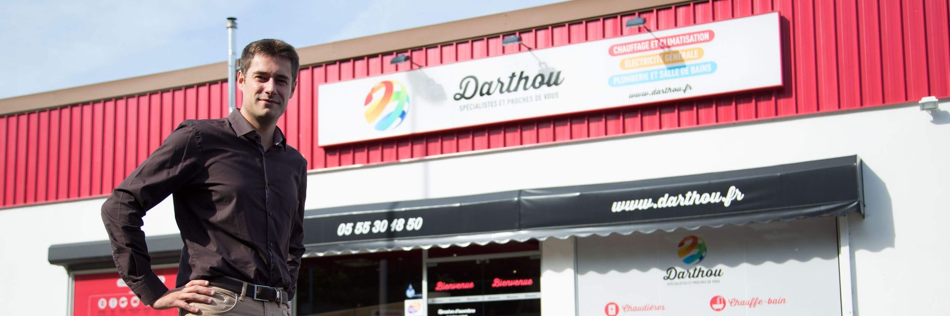 Un homme se tient devant une vitrine avec une enseigne sur laquelle on peut lire Darthau