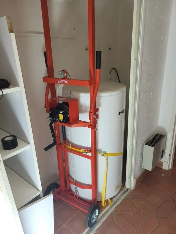 Un élévateur orange maintient un chauffe-eau blanc dans un placard.