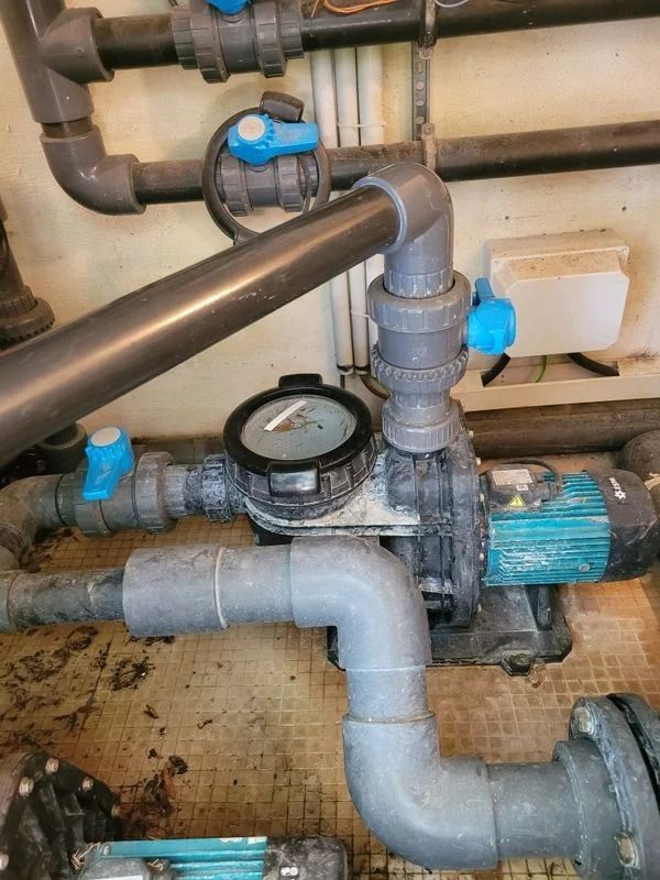 Système de pompe de piscine avec tuyaux, vannes et manomètre.