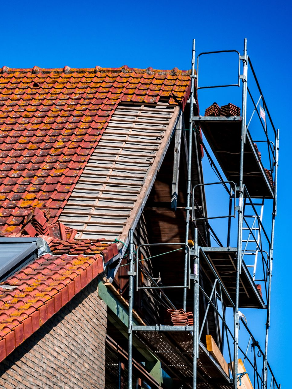Toiture en tuiles avec échafaudage sous un ciel bleu