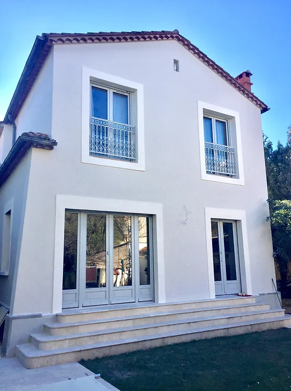 Maison blanche à un étage avec balcon et toiture en tuiles