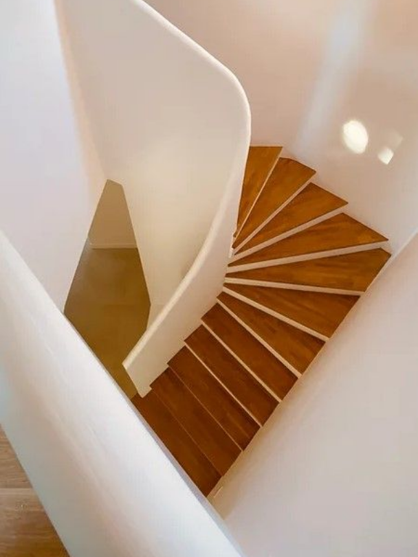 Escalier en colimaçon avec garde-corps en bois et mur blanc