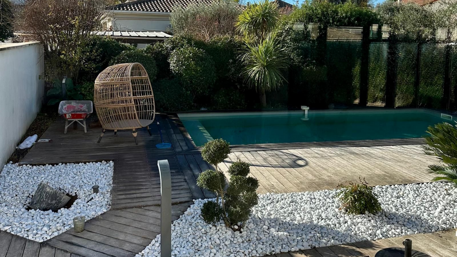 Jardin aménagé avec piscine, galets blancs et coin détente ombragé