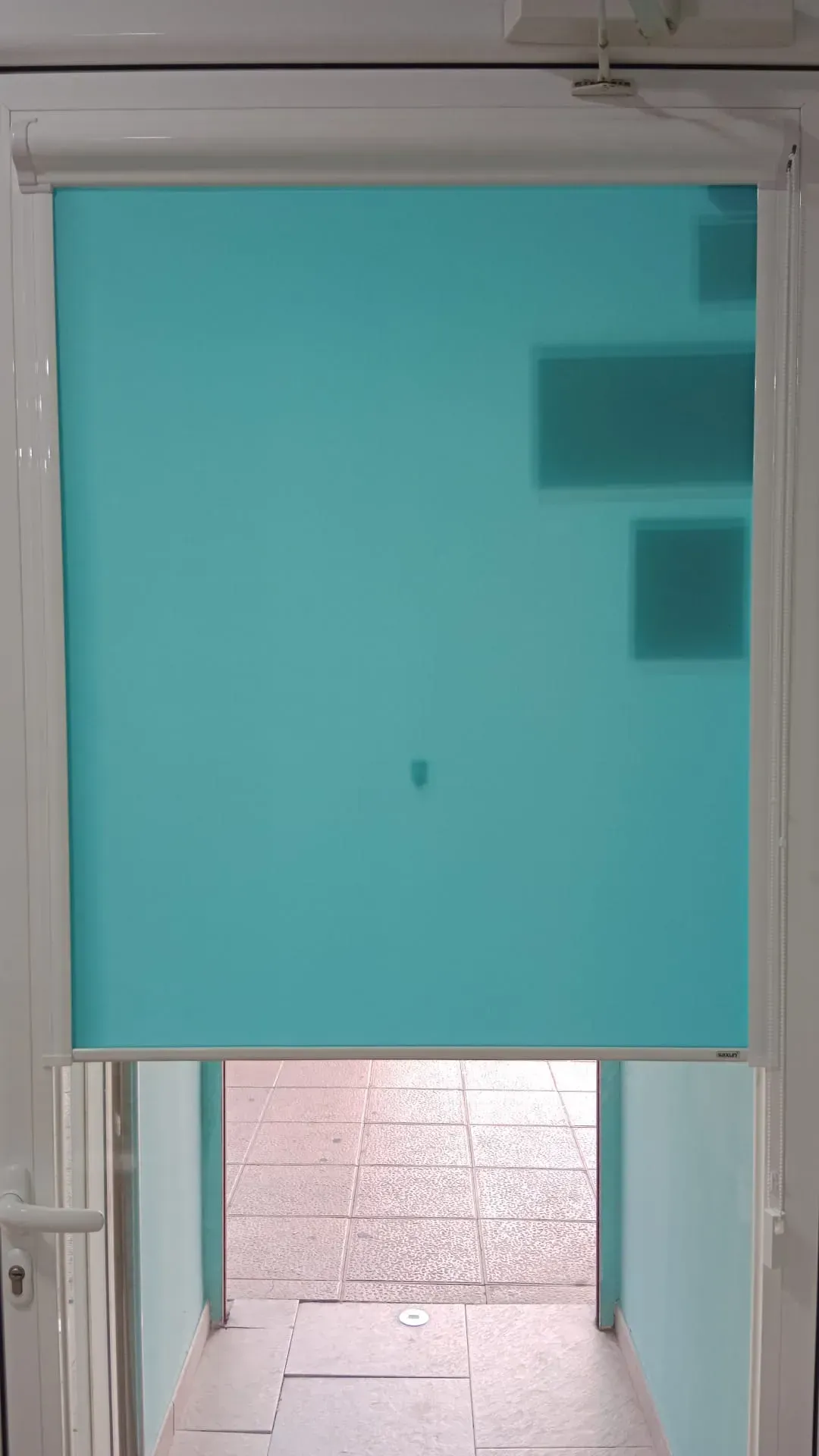 Una puerta con una persiana azul da a un pasillo.