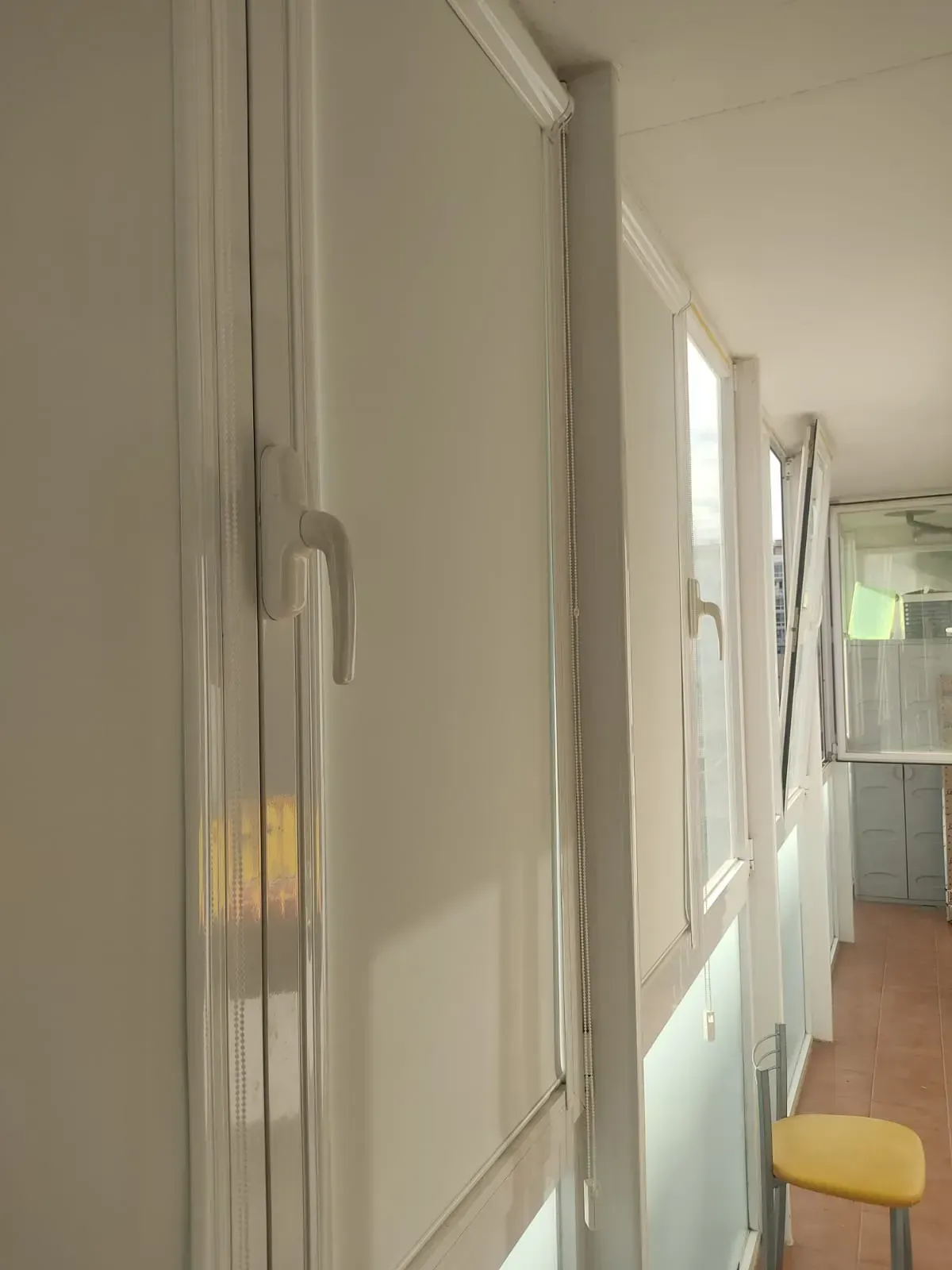 Un largo pasillo con paredes blancas y una silla amarilla.