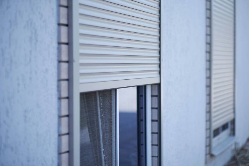 Un primer plano de una ventana con una persiana enrollable.