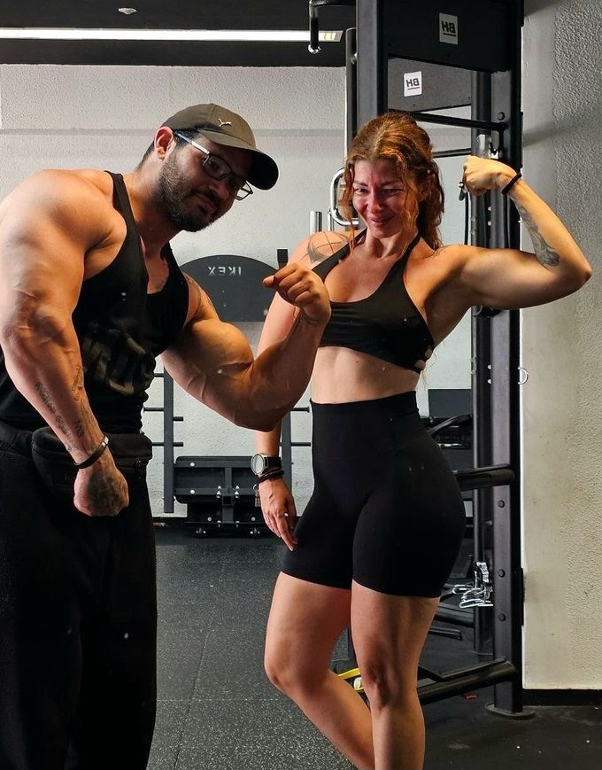 Dos personas que van al gimnasio a mostrar sus músculos en una sala de pesas