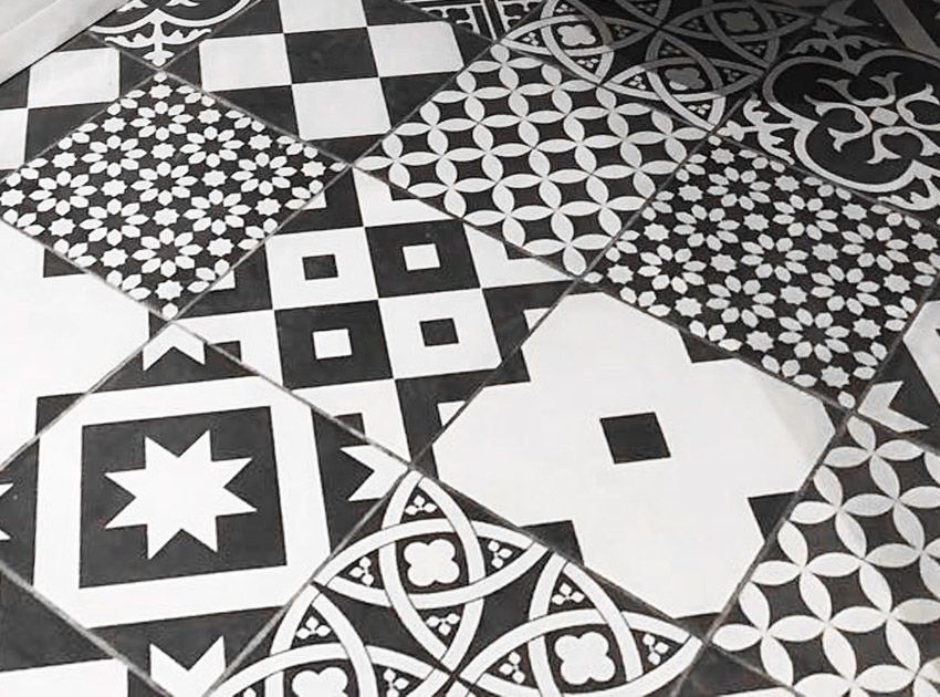 Carrelage de sol à motifs noirs et blancs présentant divers dessins géométriques et floraux.