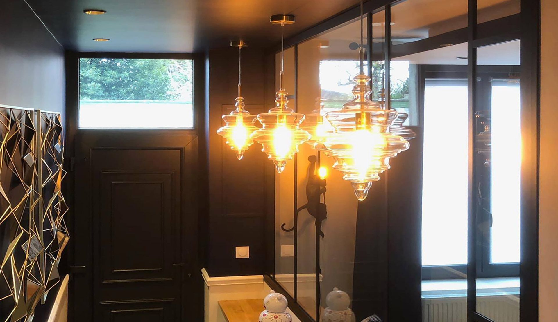 Couloir sombre avec trois suspensions lumineuses et un mur de miroirs.