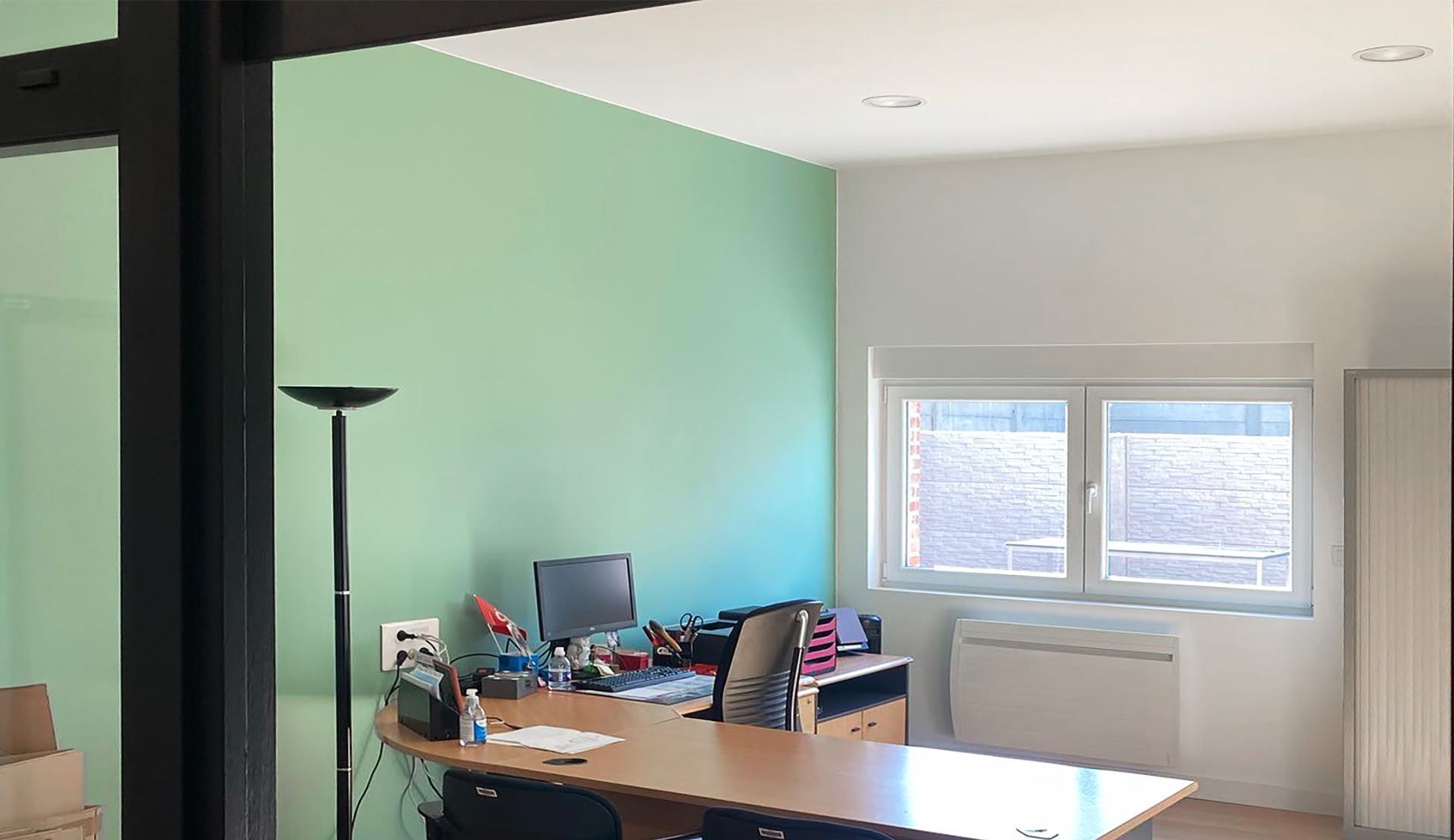 Intérieur de bureau avec bureau, ordinateur, mur végétal, fenêtre.