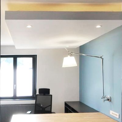 Intérieur de bureau avec bureau, mur bleu, fenêtre, lampe moderne et spots encastrés au plafond.