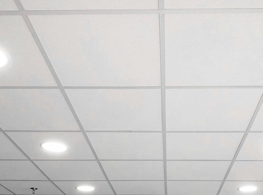 Dalles de plafond blanches disposées en grille avec spots encastrés.