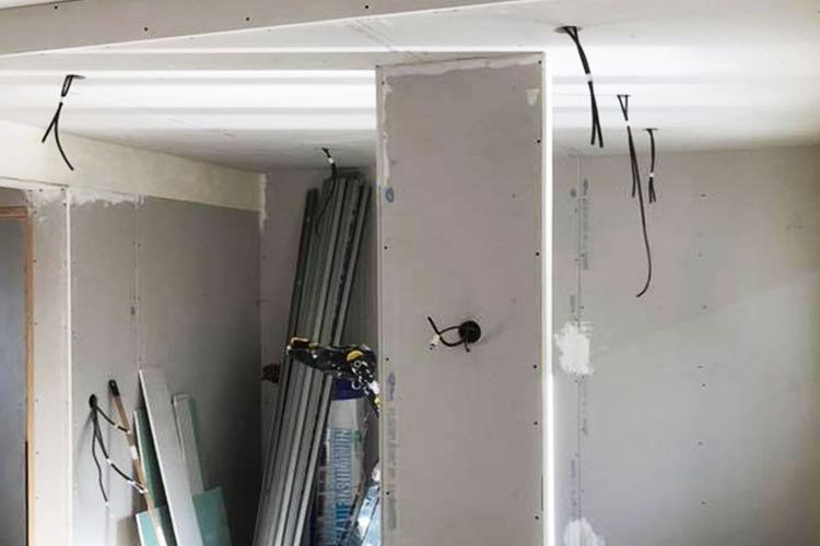 Intérieur en travaux avec câblage apparent, cloisons sèches et éléments structurels.
