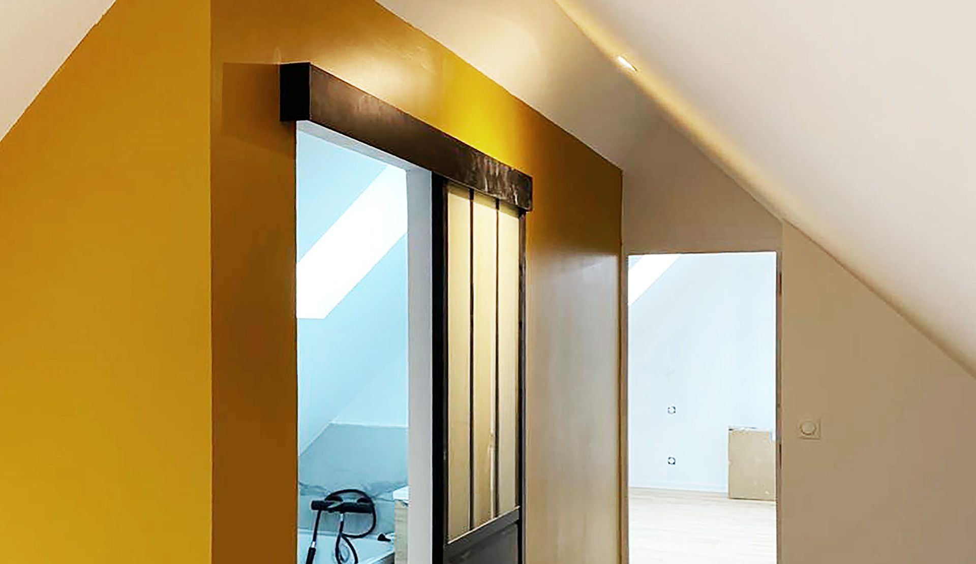 Intérieur avec mur jaune moutarde, porte coulissante en verre et plafond blanc cassé.