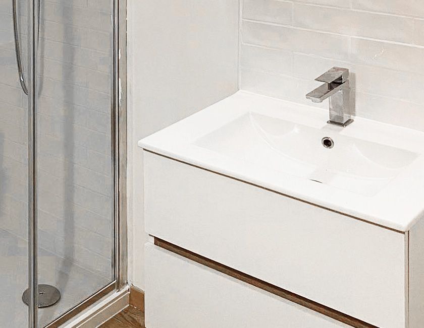 Meuble-lavabo blanc avec robinet et cabine de douche.
