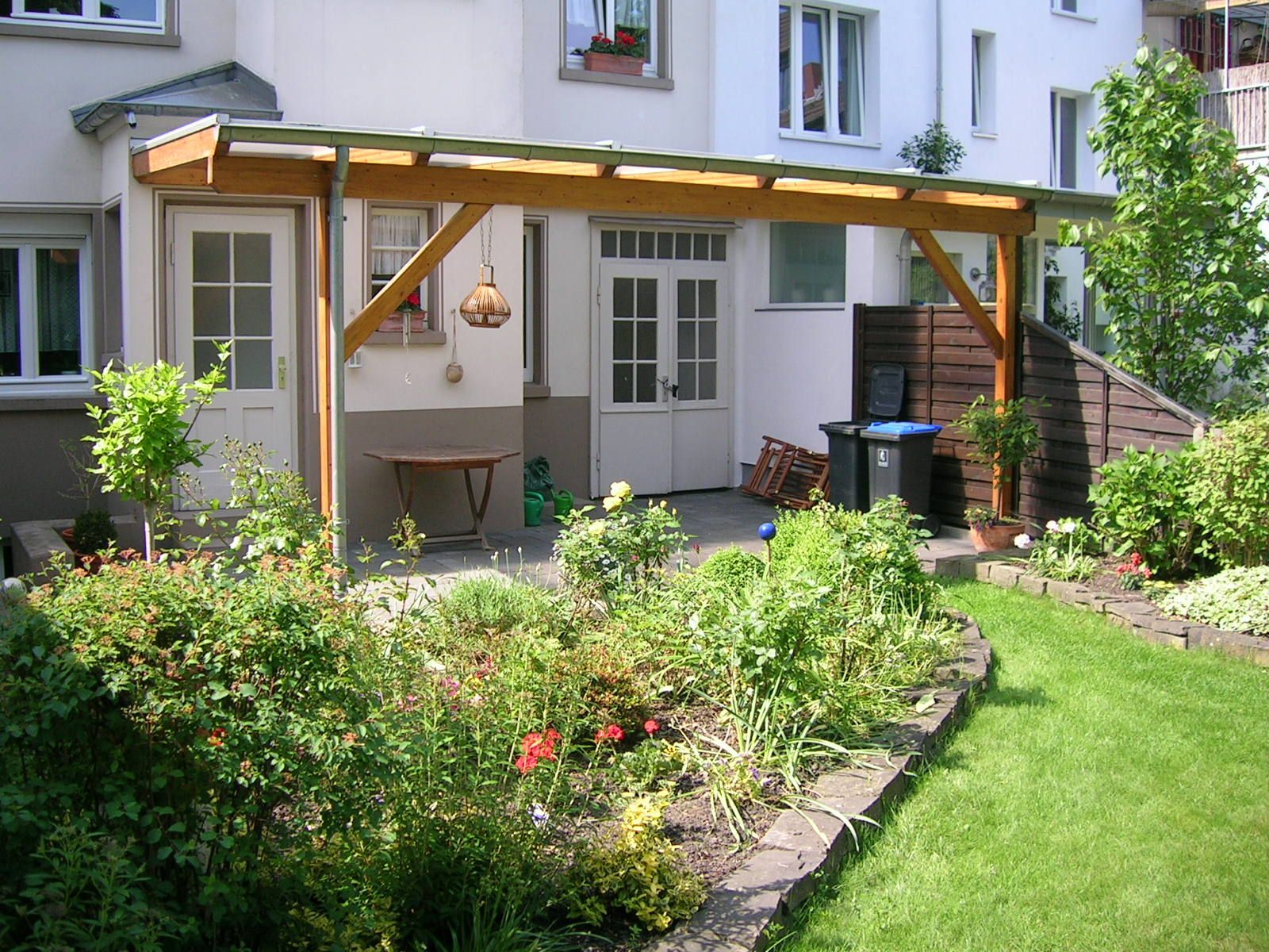 Ein weißes Haus mit einer hölzernen Pergola davor