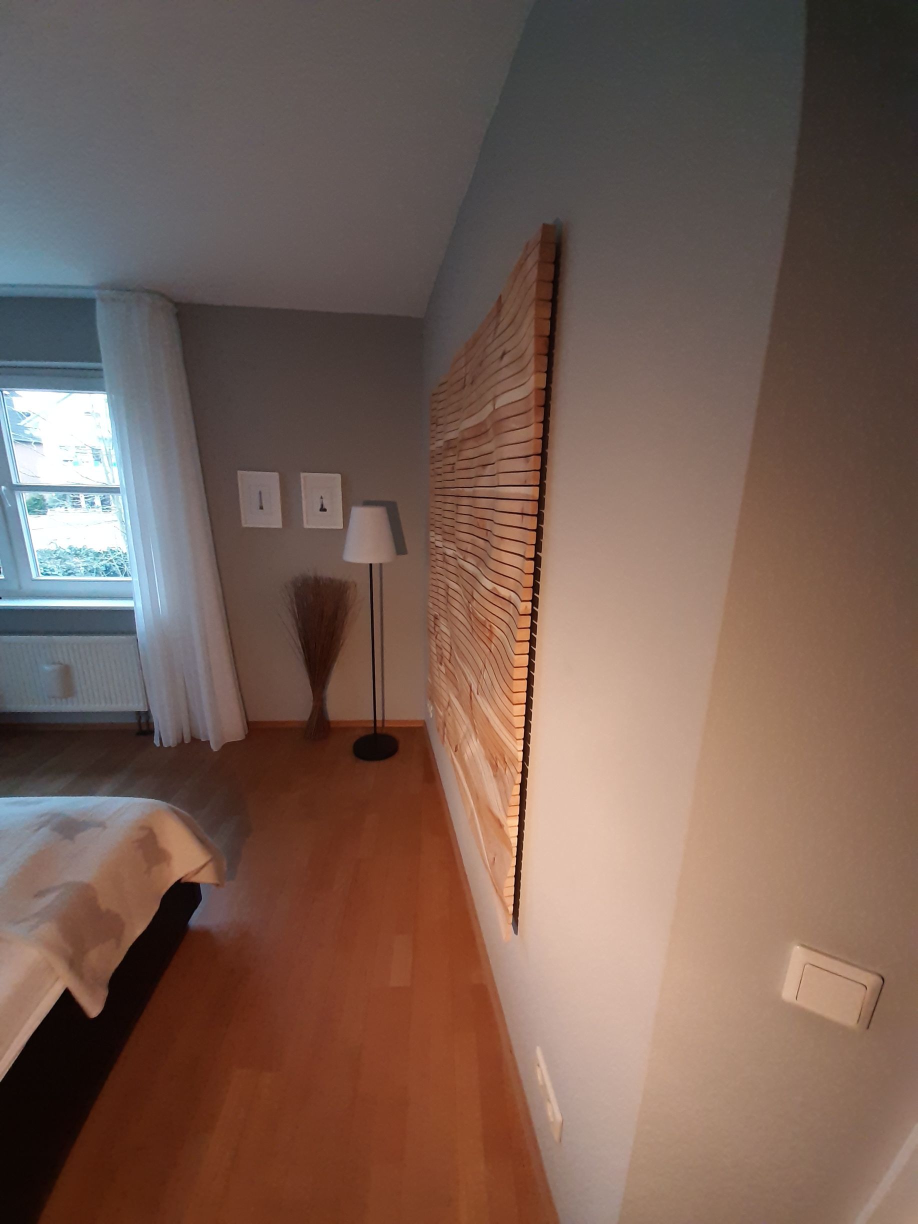 Ein Schlafzimmer mit einem Bett, einer Lampe und einem großen Gemälde an der Wand.