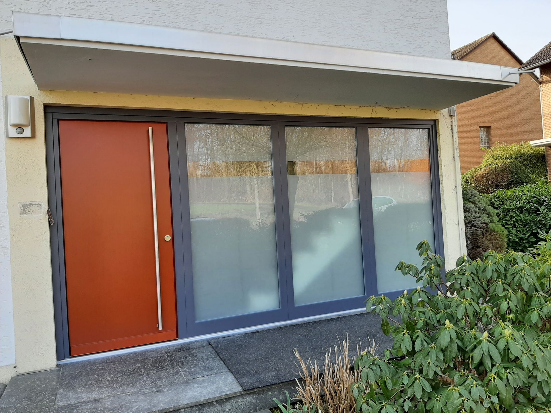 Ein Haus mit einer roten Tür und vielen Fenstern